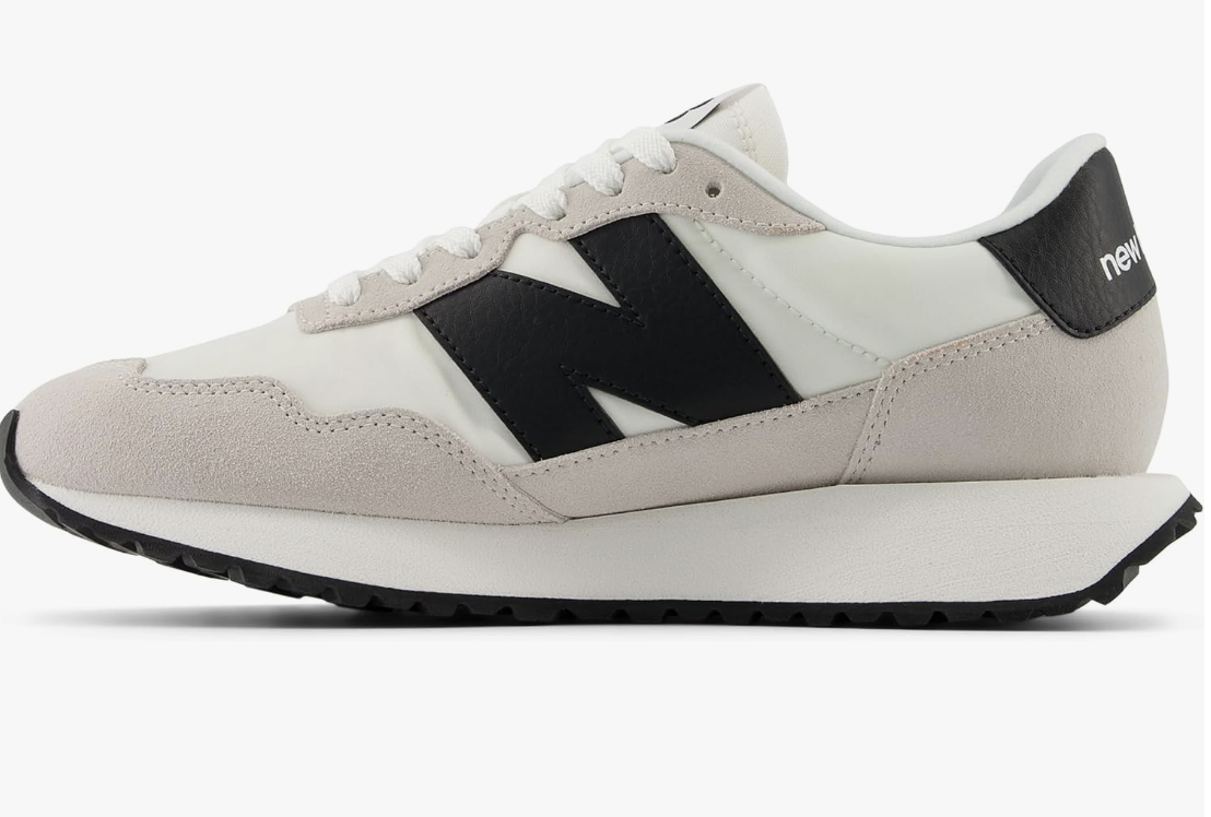 A pair of New Balance Women's 237 V1 Sneakers in sea salt and black, styled with high-waisted satin trousers and a bodysuit for a balanced, chic look.