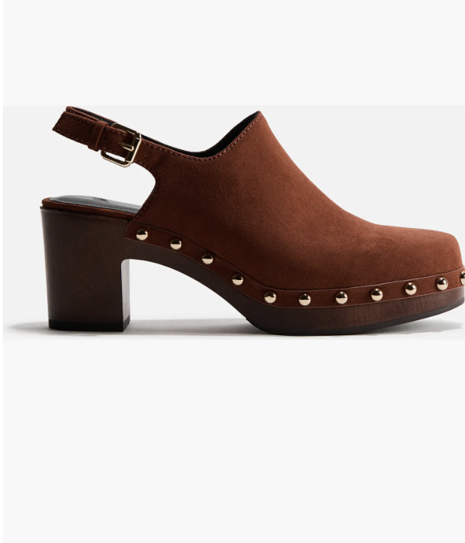 A close-up shot of a dark brown leather platform clog shoe featuring a chunky wooden block heel and polished gold stud detailing along the sole.
