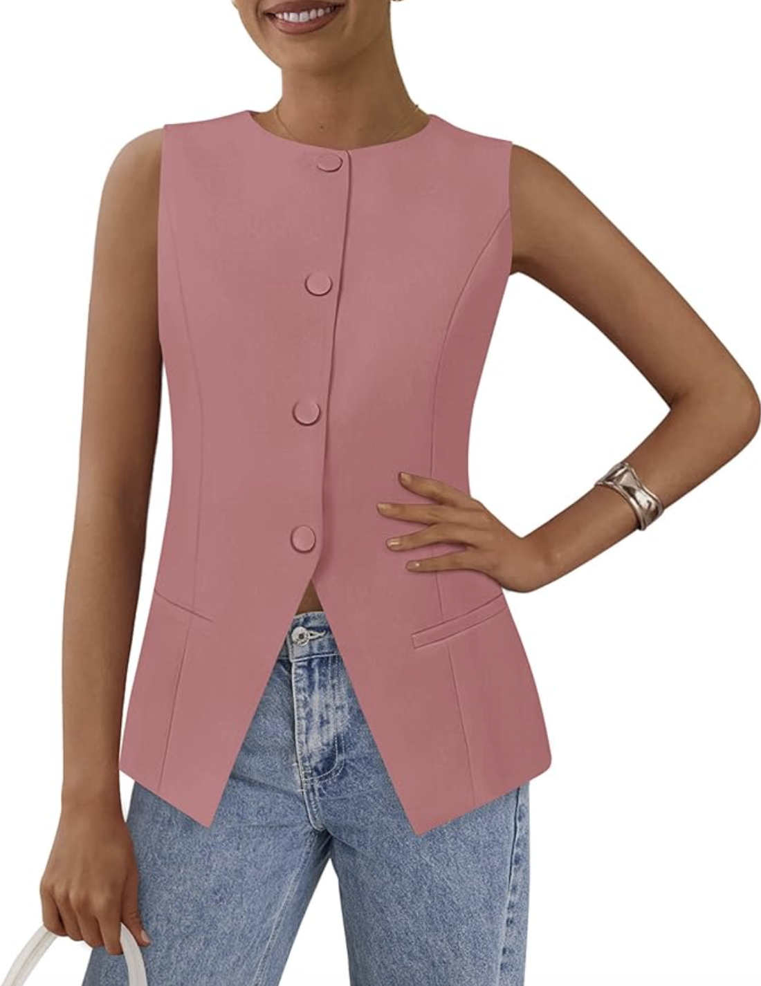 Close-up of a woman wearing a sleeveless, structured blush pink suit vest with a button-front closure and an asymmetrical split hem, paired with light-wash denim jeans.