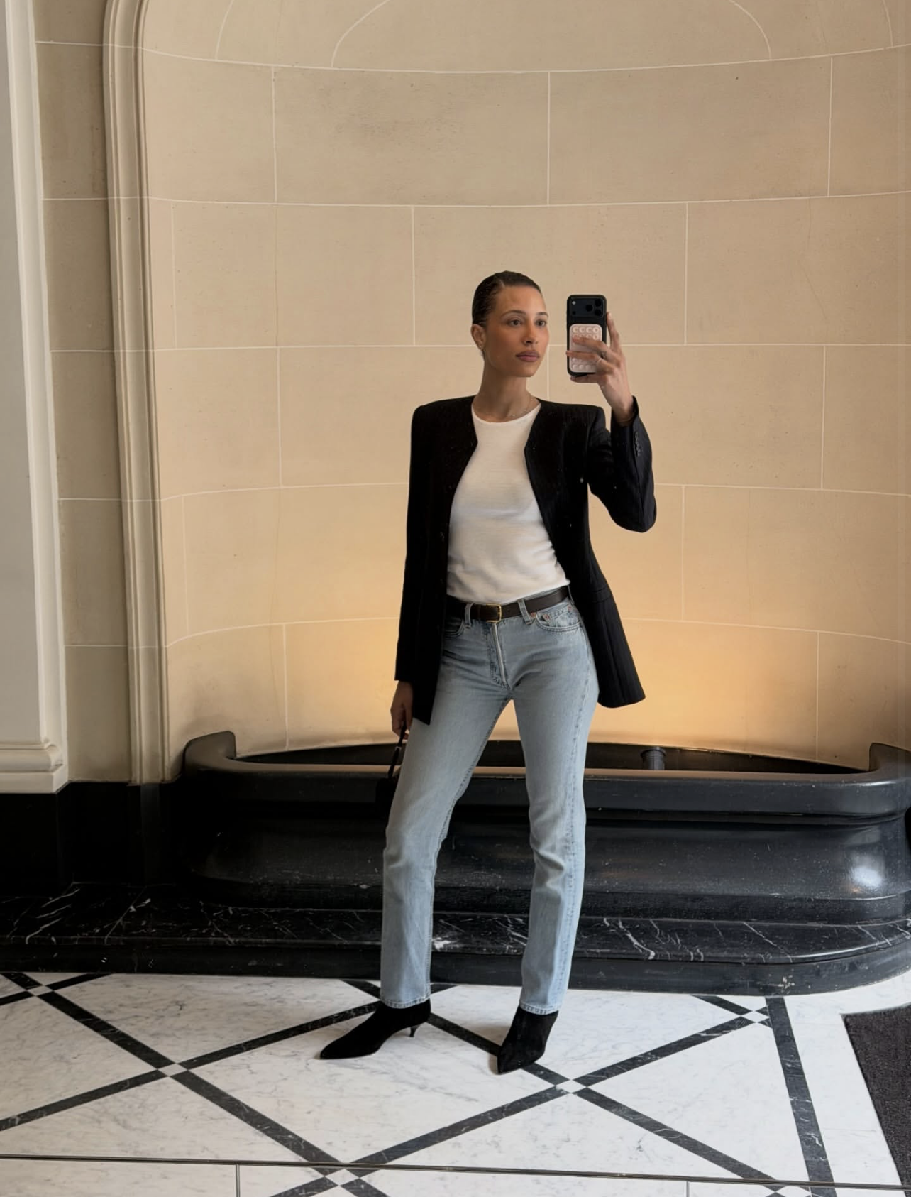 TyLynn Graham wearing a black tailored blazer, white t-shirt, and slim-straight light wash jeans with black pointed-toe boots.