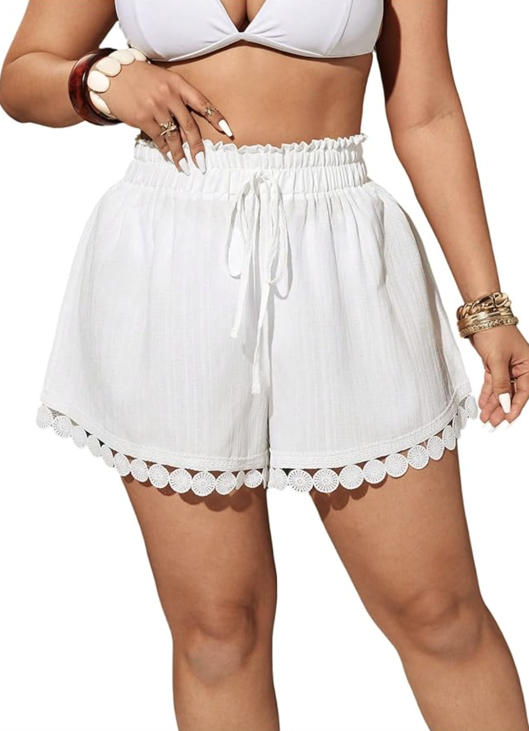 Close-up of white high-waisted shorts featuring a detailed circle-lace trim along the hem.