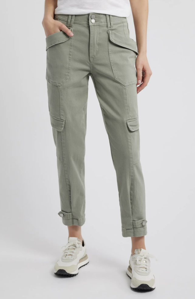 A person wearing light green cropped linen cargo pants with an elastic waistband, large side pockets, and adjustable drawstring hems, paired with white and black sneakers.