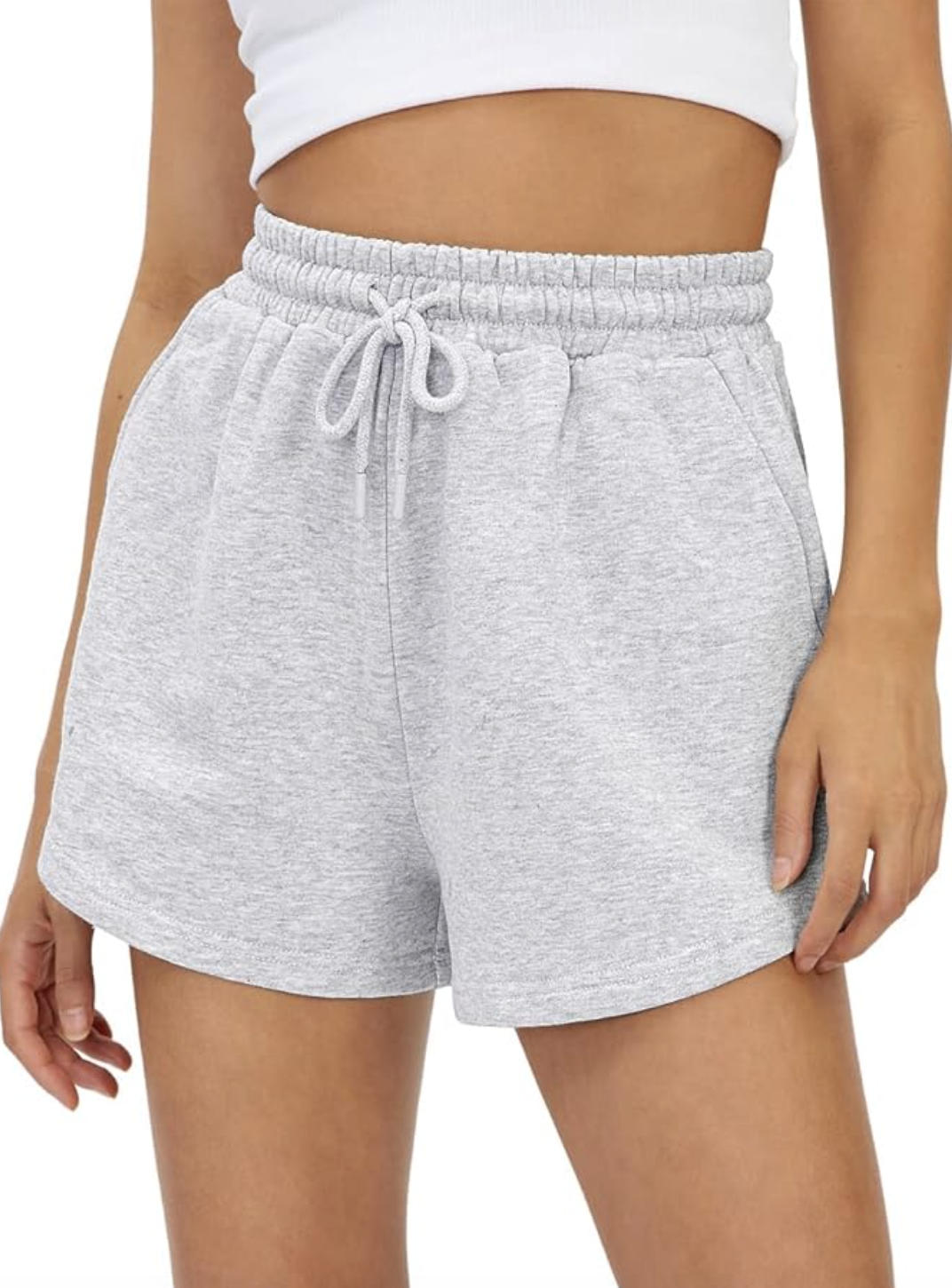 A pair of grey high-waisted sweat shorts with a drawstring and side pockets, styled for a travel outfit.