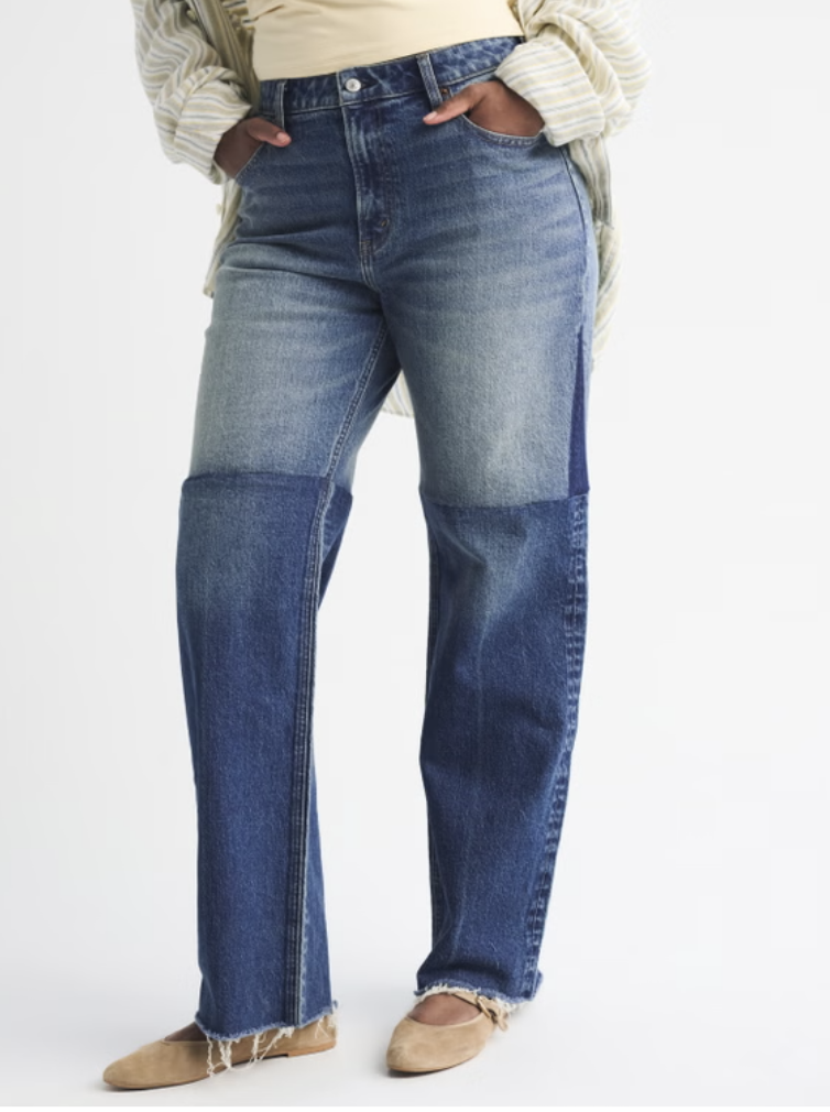 A woman wearing Abercrombie Curve Love High Rise 90s Relaxed Reworked Jeans in a medium wash with a raw hem and tan ballet flats.