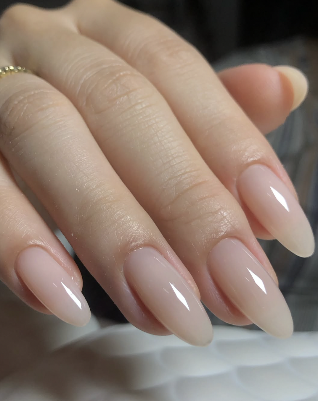 Long almond shaped nails with a sheer soft-white structured manicure and a high-gloss finish.