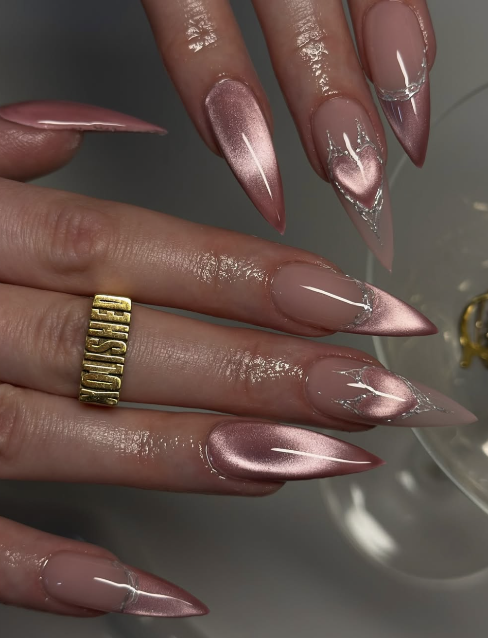 A close-up of long, tapered nails with a dusty rose pink chrome finish and a high-shine metallic reflection.