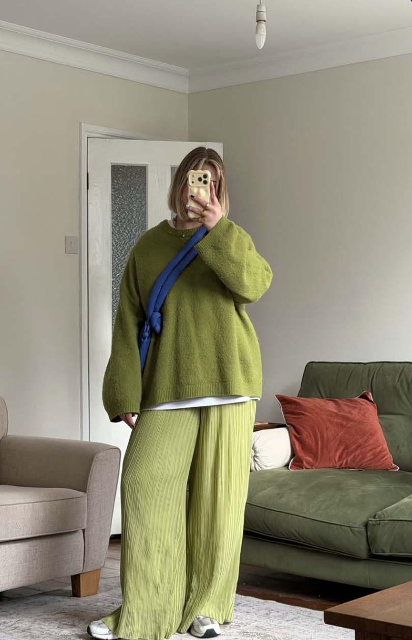 A woman wearing a lime green oversized sweater and matching pants with a bright cobalt blue crossbody bag.