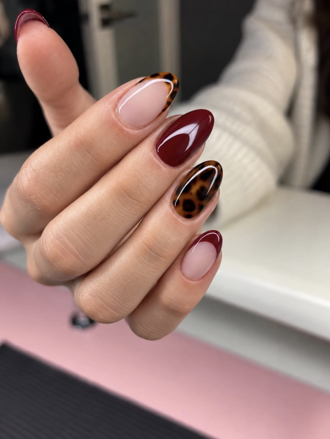 Short oval nails painted glossy chocolate brown with a strawberry-red accent nail.