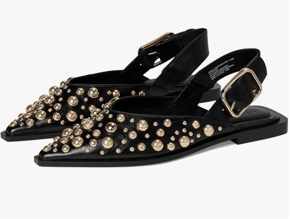 A pair of black pointed-toe slingback ballet flats featuring all-over gold stud embellishments and a buckled ankle strap, styled as a modern footwear essential for women in their 50s.