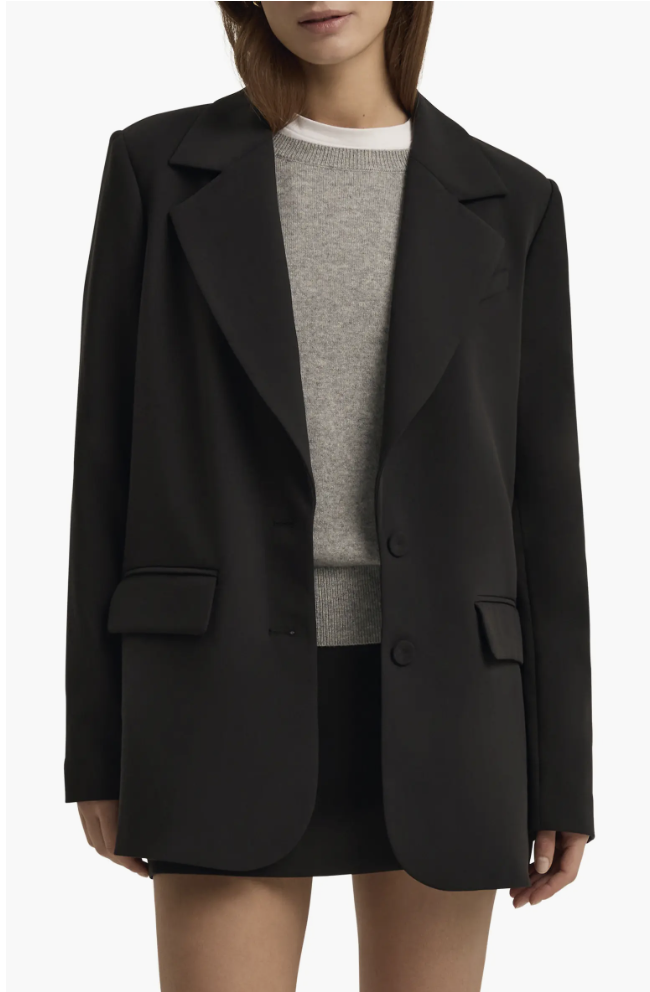 A person wearing a structured black oversized blazer with a crew neck sweater, styled as part of a professional cargo pant outfit.