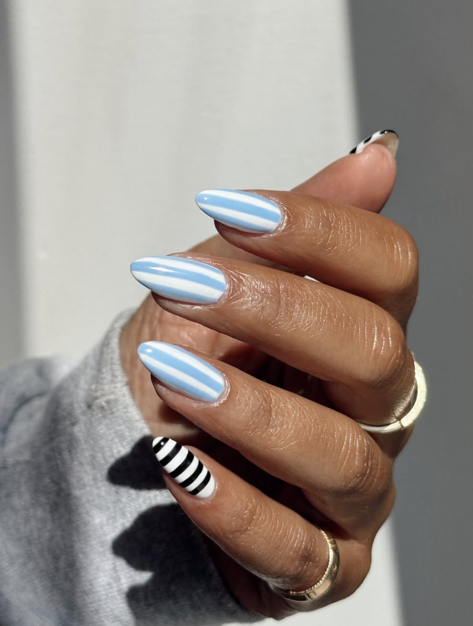 Long almond-shaped nails featuring a sky blue and white base with thin horizontal black and white stripes.