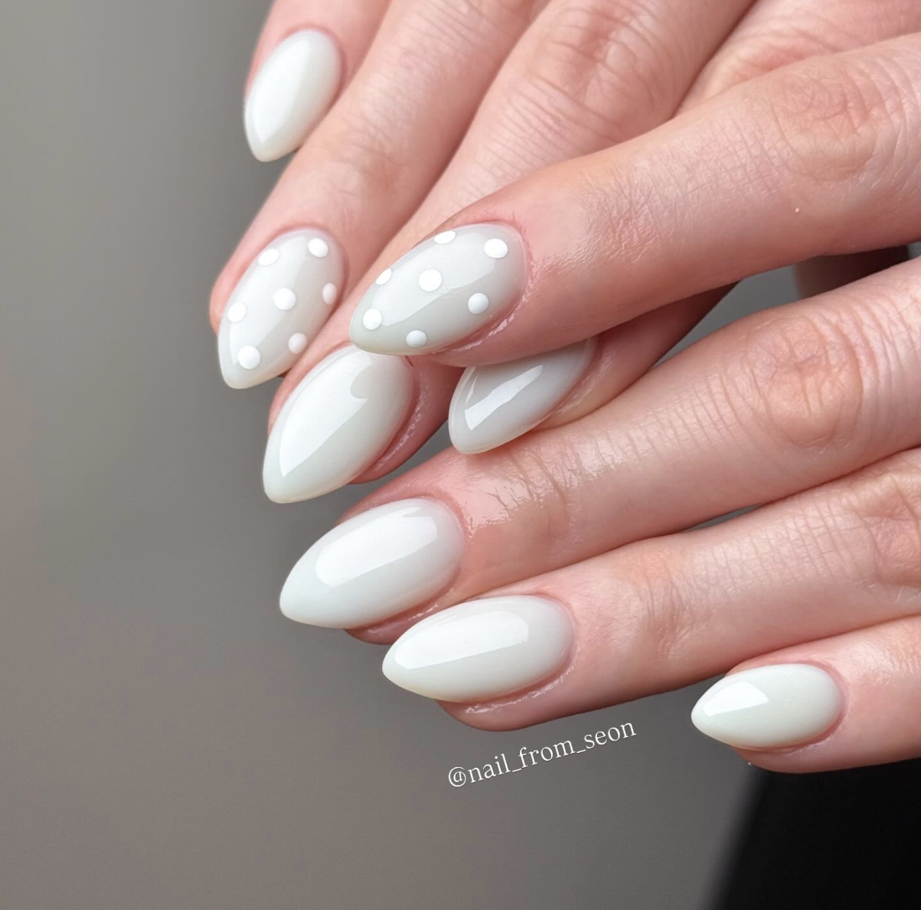 Long, almond-shaped nails featuring a soft mint green base coat with a luminous pearl chrome glaze, accented by clean white polka dots.