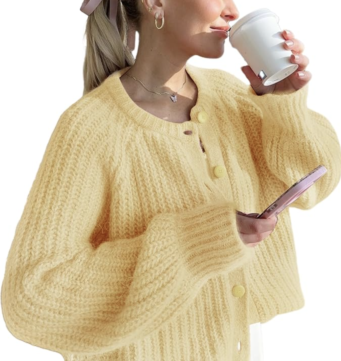 A woman wearing a yellow chunky knit open-front cardigan over a white top, holding a coffee cup.