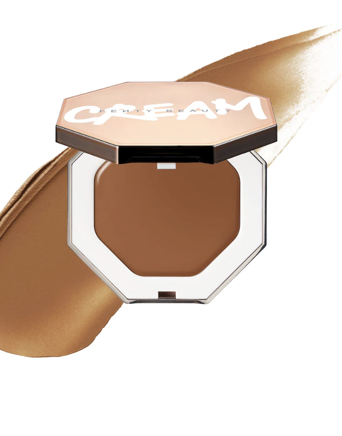 An open compact of Fenty Beauty Cheeks Out Freestyle Cream Blush in a deep berry shade with a smooth cream swatch in the background.