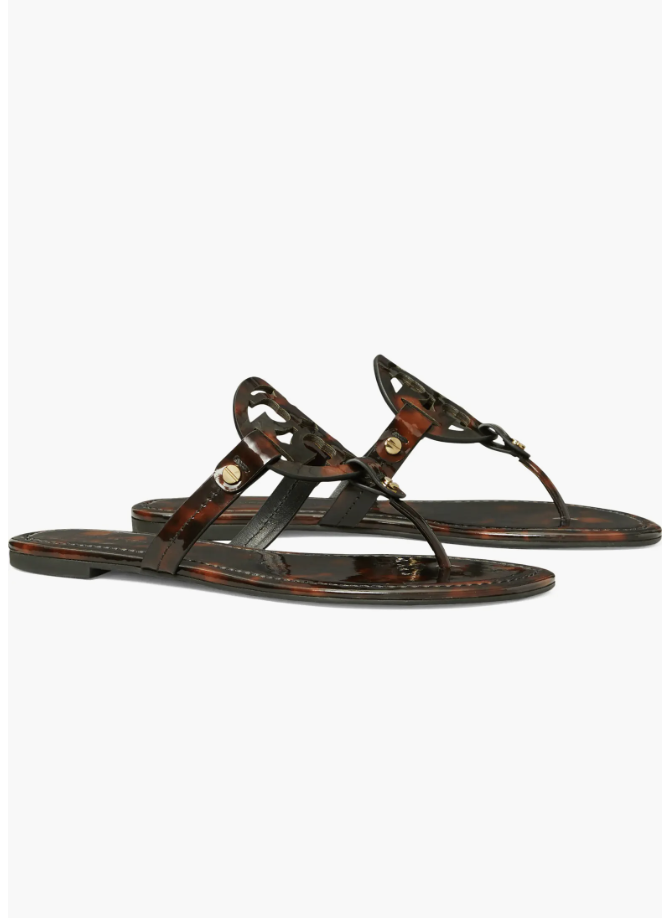 A pair of Tory Burch Miller thong sandals in a dark tortoiseshell pattern with the iconic gold logo, a classic designer shoe to pair with white straight-leg jeans.