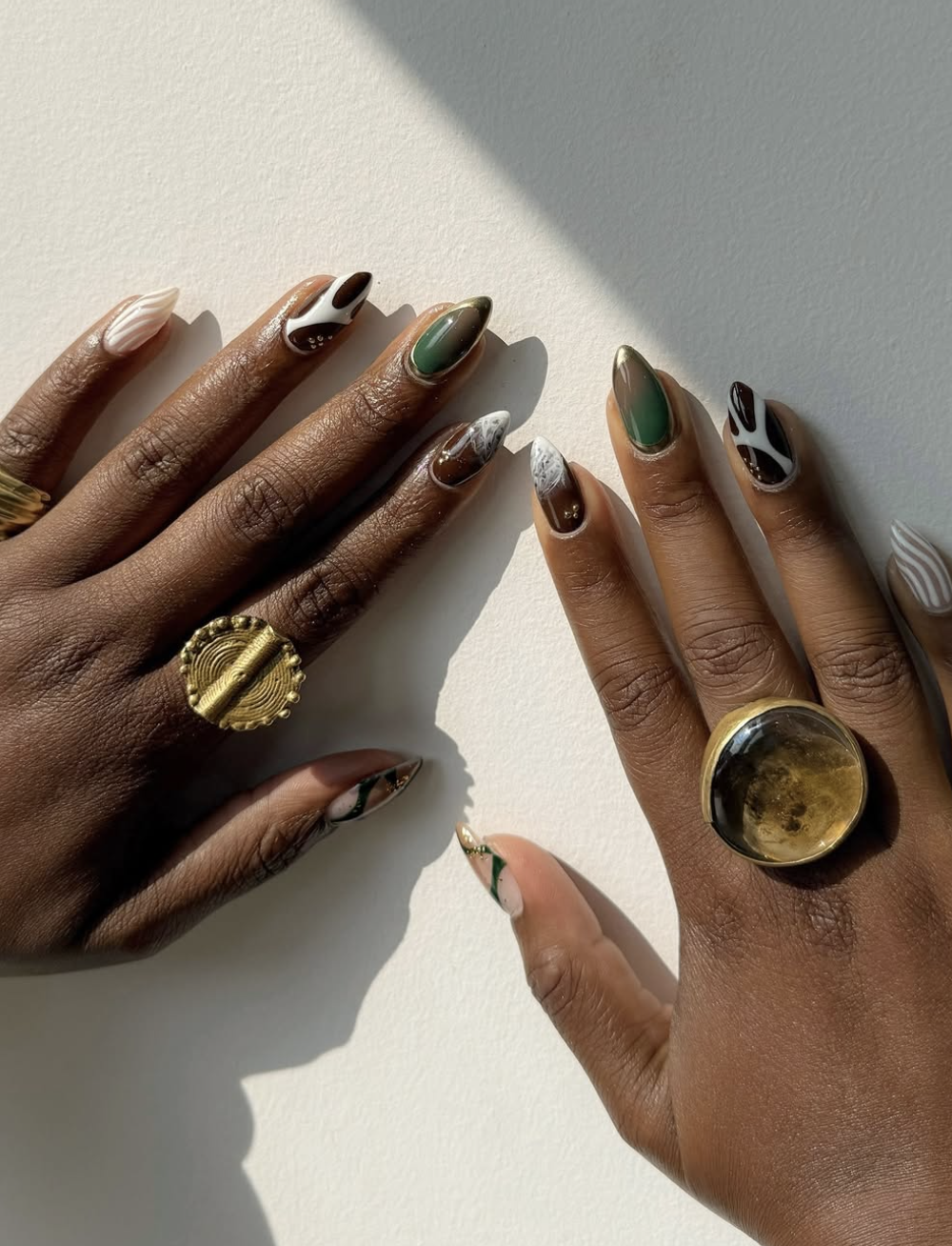 Long almond-shaped gel nails with a neutral base and delicate, hand-painted abstract swirls.