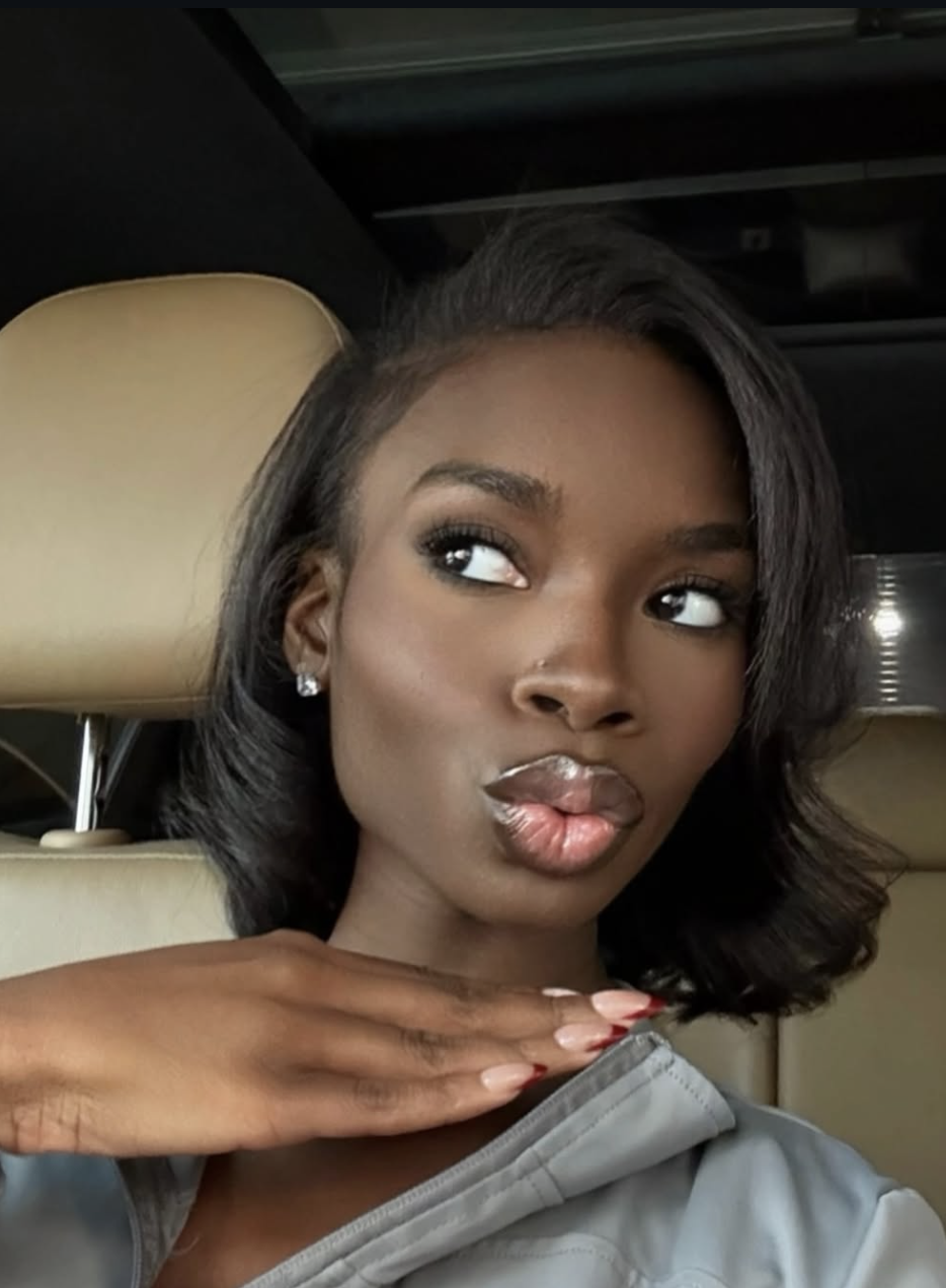 A woman with a voluminous, side-parted natural hair blow-out that frames the face with soft texture to balance a wider forehead and narrow chin.