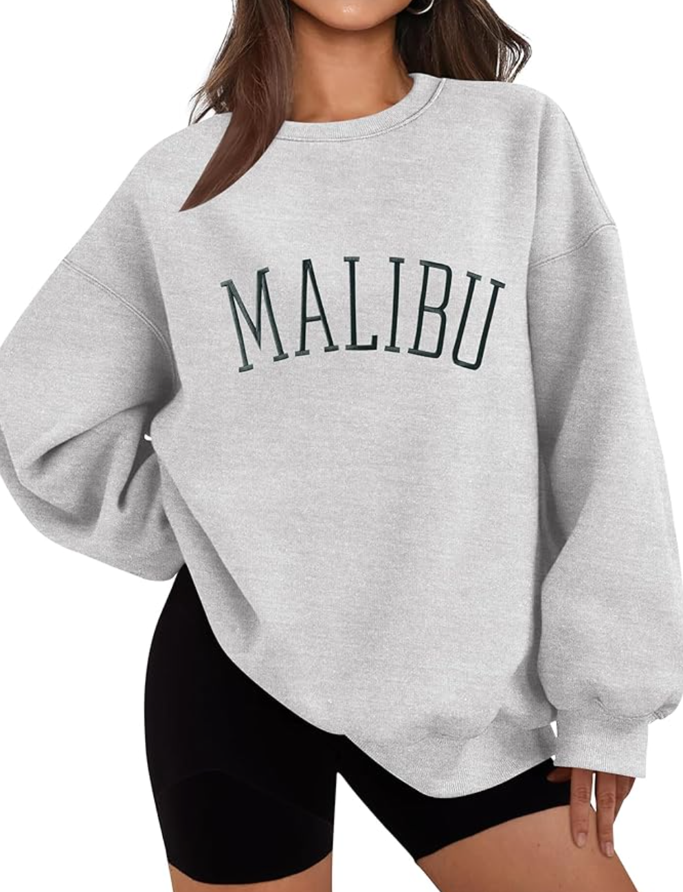 A woman wearing a grey oversized Malibu graphic crewneck sweatshirt and black biker shorts for a Santa Monica travel outfit.