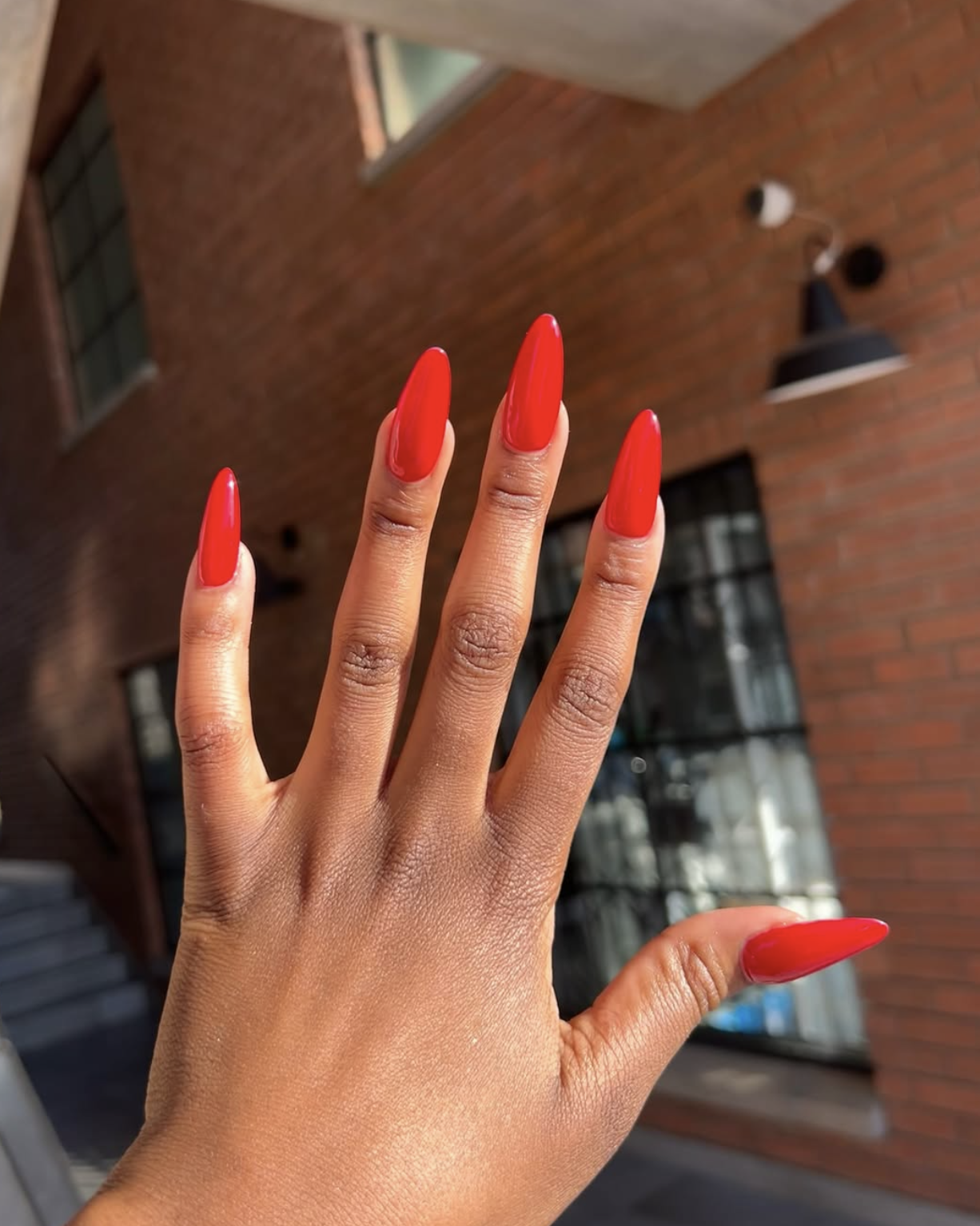 Tomato-red nail polish on almond-shaped nails