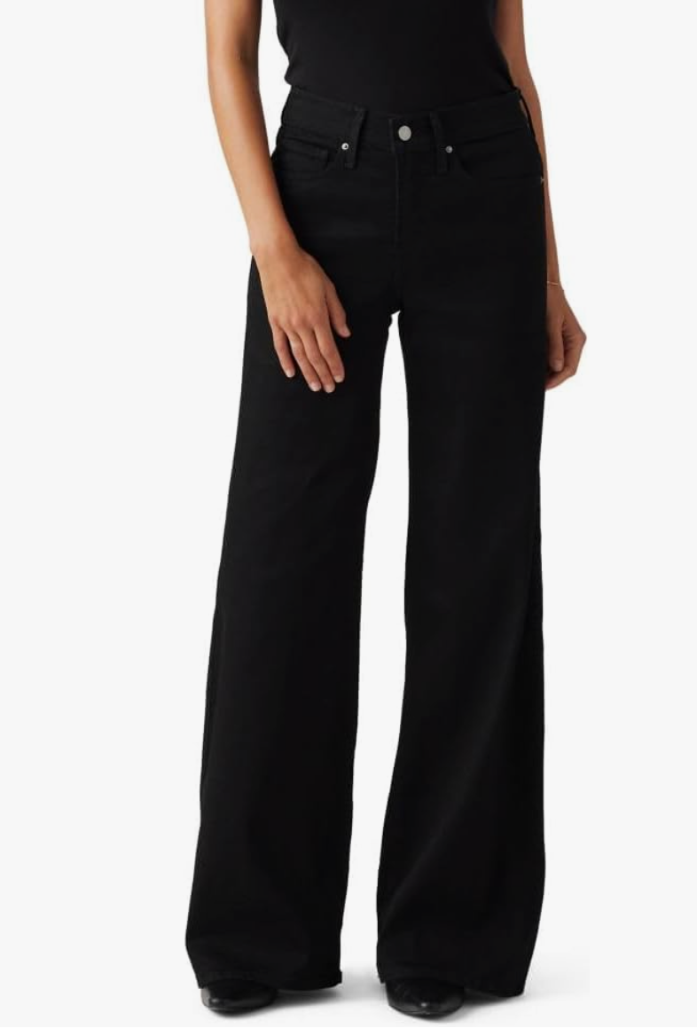 A woman wearing a tan cropped double-breasted trench coat paired with high-waisted denim to visually shorten a long torso and elongate the leg line.