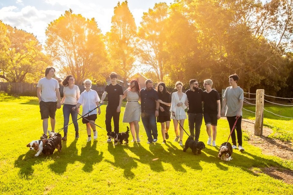Extended family walking with dogs in bright afternoon sun at Fagan Park