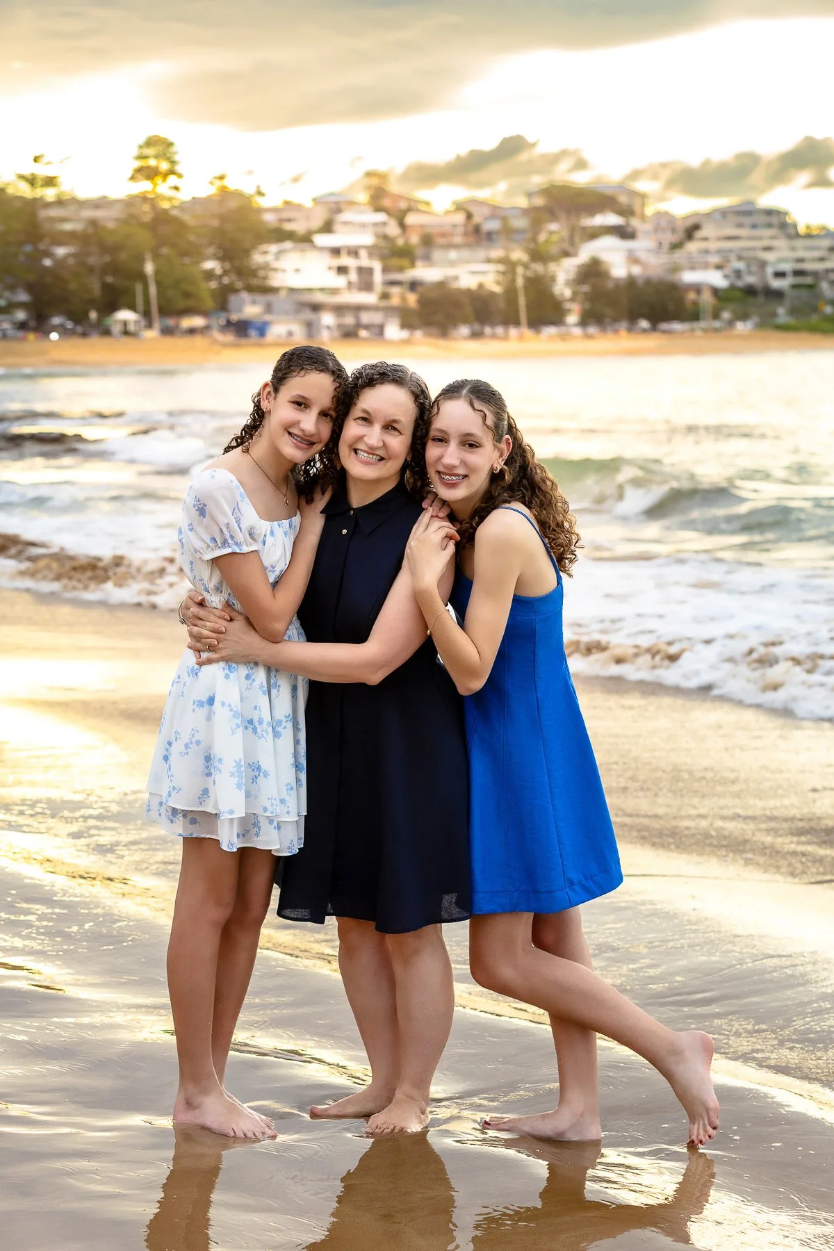 A mother with her two teenage daughters on the beach during a sunset family photoshoot in Sydney