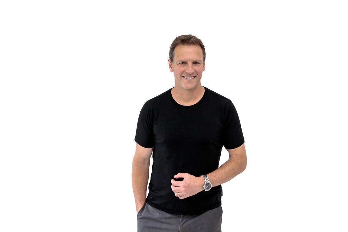 Middle aged man in front of white wall with hand in pocket