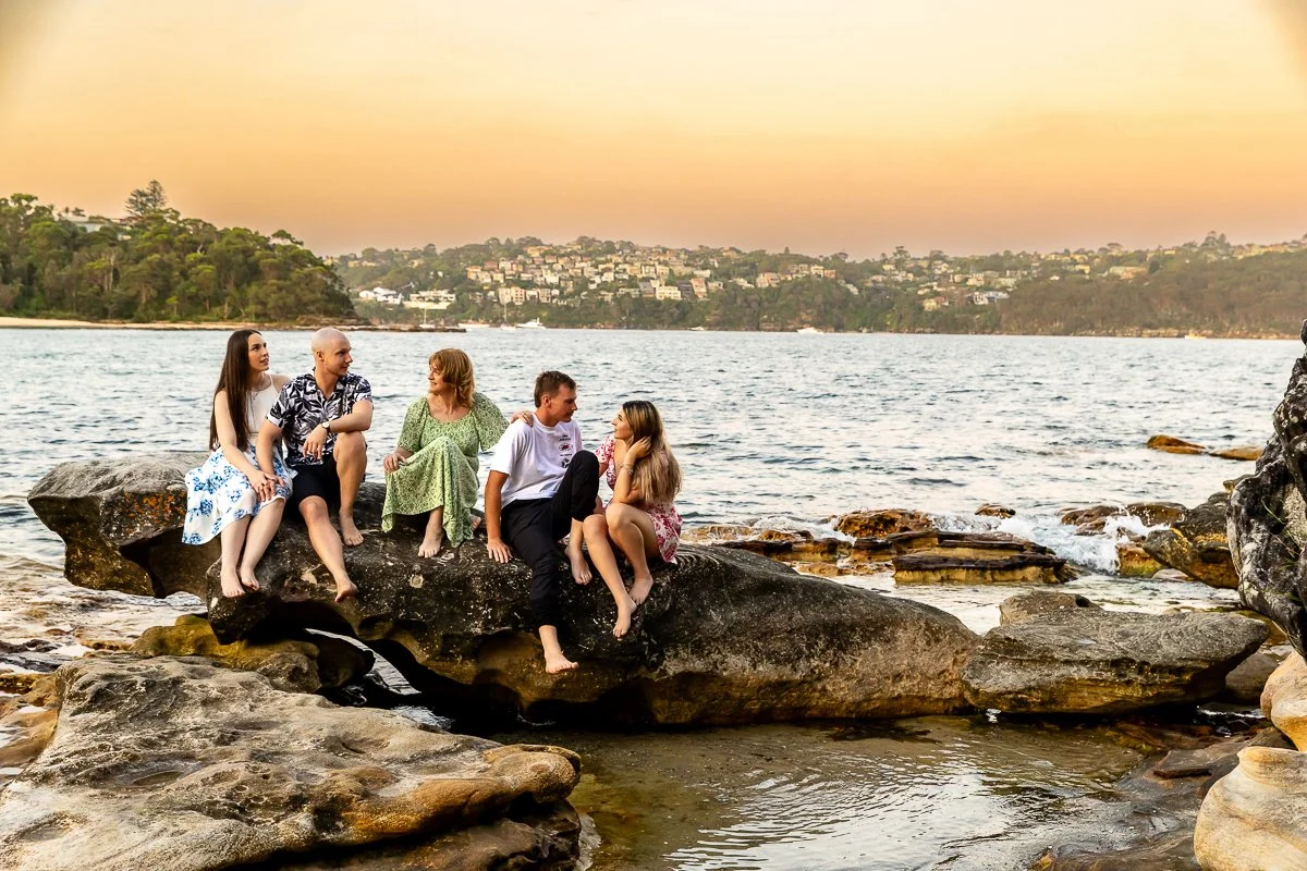 A family sitting in the rocks at Balmoral Beach in Sydney's Lower North Shore during a sunset family photoshoot