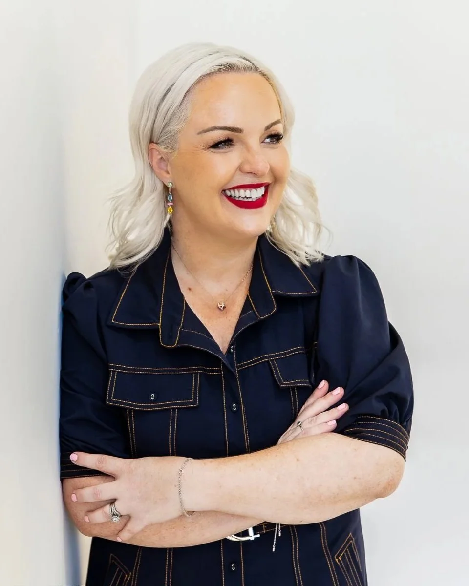 A woman in a blue dress is leaning against a wall during her branding photography session in a studio