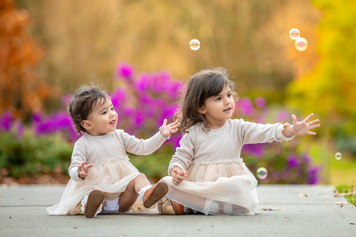 Young sisters sitting playing with bubbles
