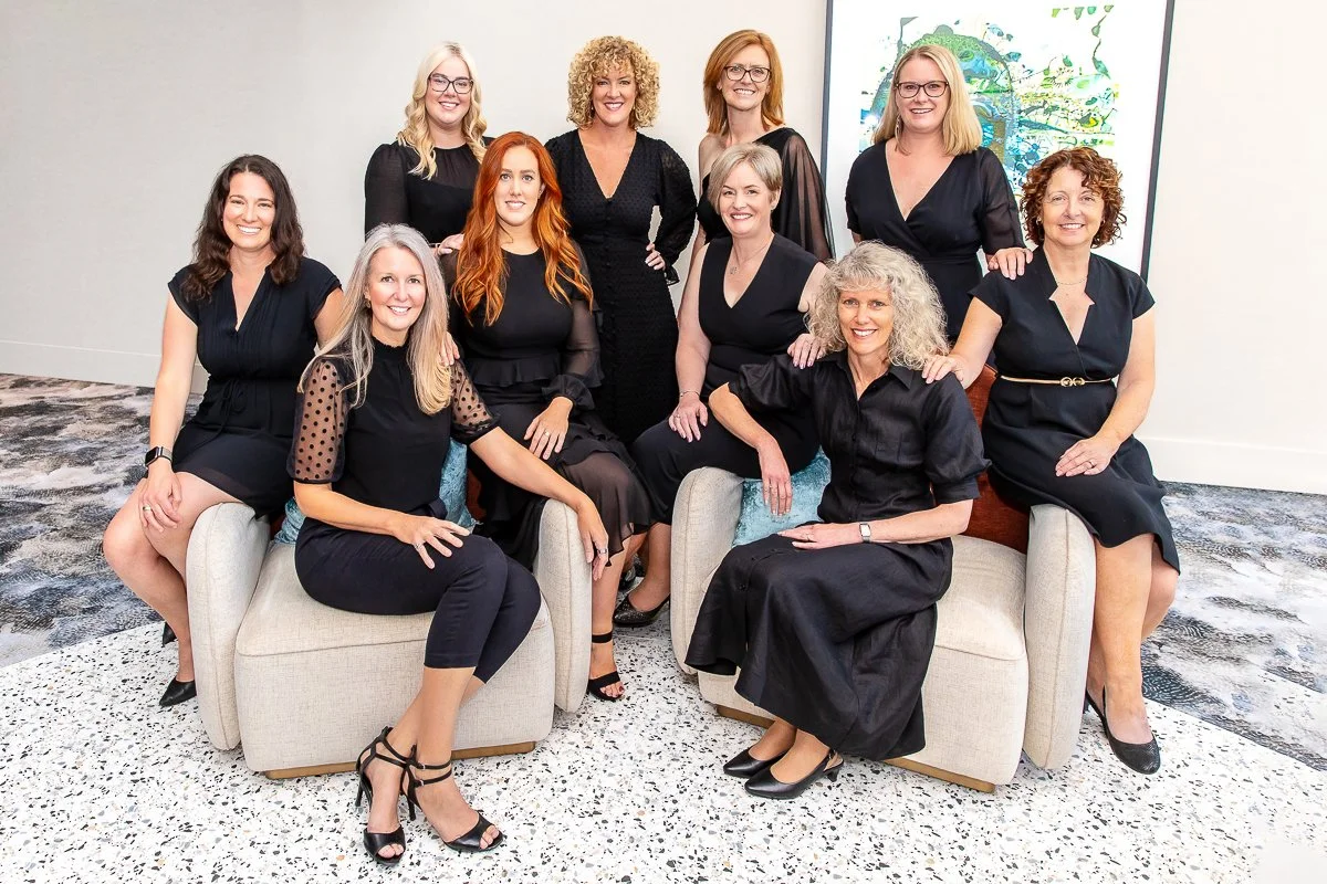 A group of business woman dressed in black sitting as a group looking at the camera during a branding photoshoot