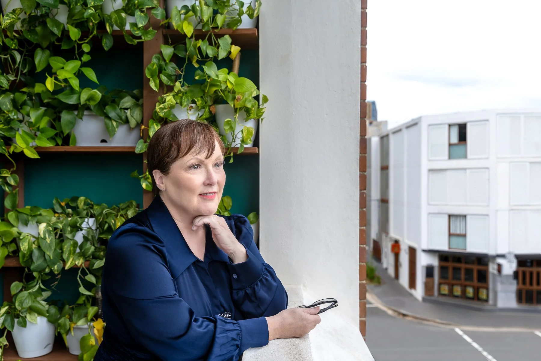 A woman on a balcony looking pensive out to the side during her branding session