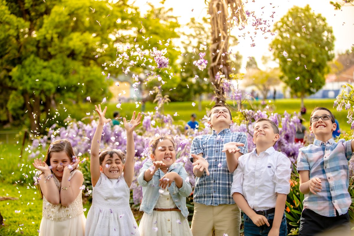 Cousins throwing up flowers in front of blossoms at Parramatta Park