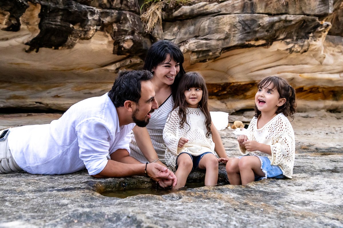 A young family exploring a rock pool together at Balmoral Beach during a family photoshoot