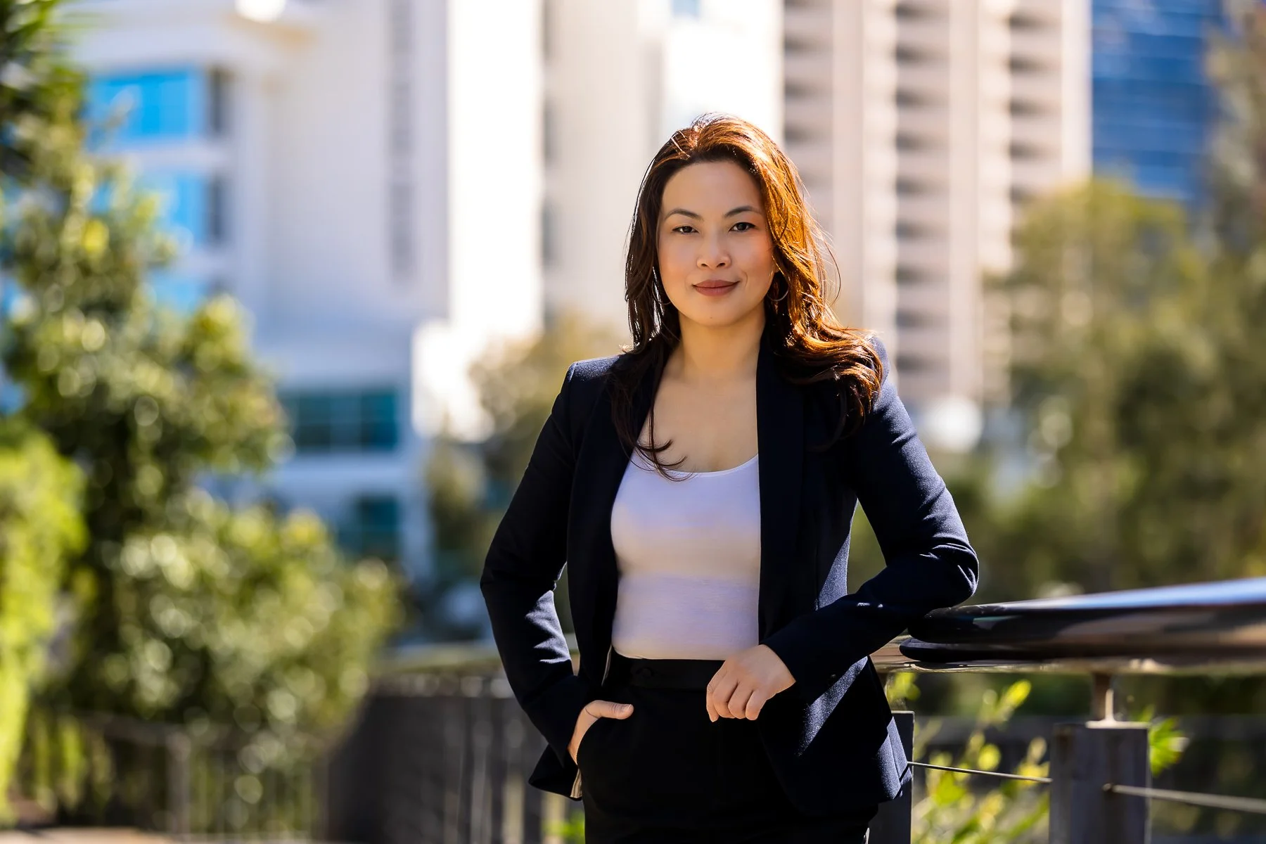 A woman is standing in an outdoor setting with business buildings in the background.  She is standing in a power pose during her personal branding shoot in Norwest in Sydney's Hils District.