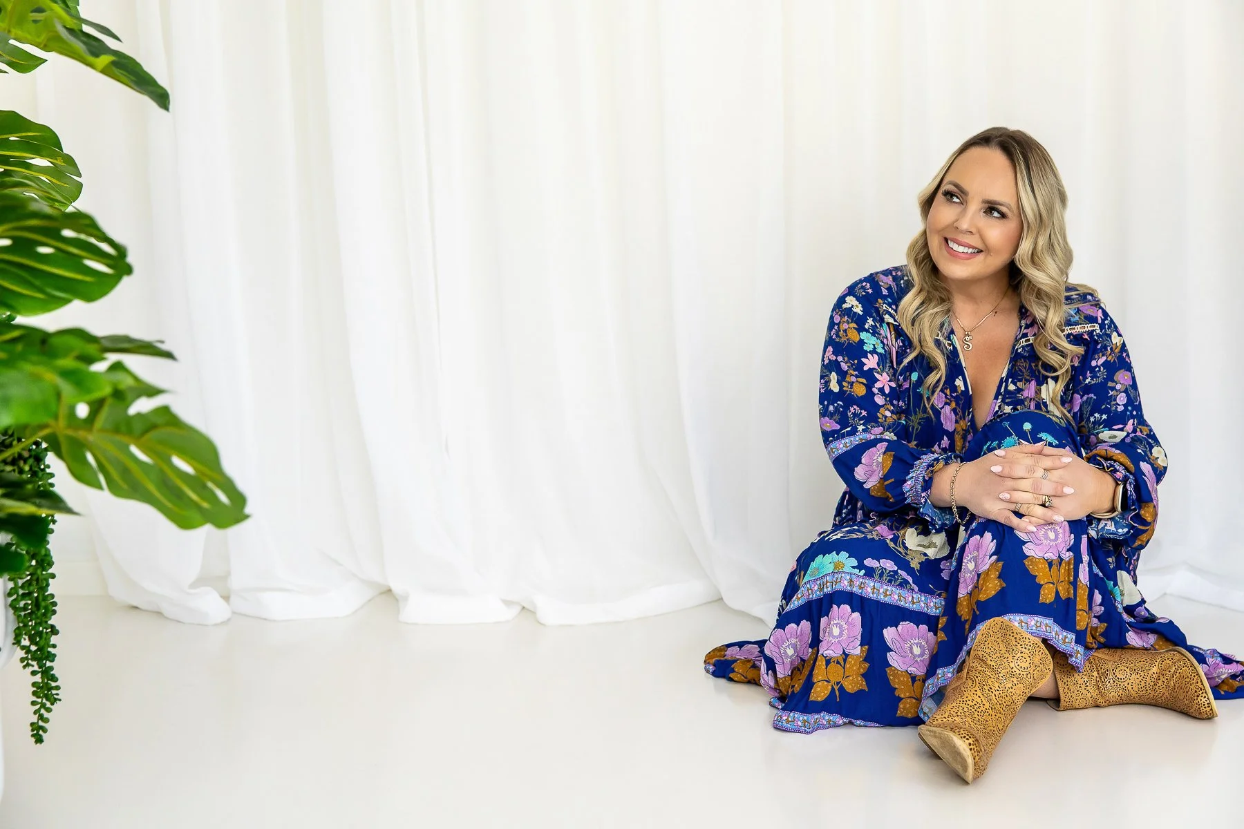 A woman in her 40's sitting on the ground looking to the side during a branding photoshoot in the Castle Hill studio