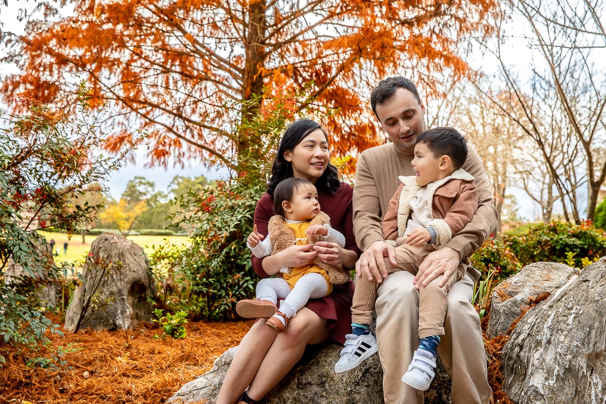 Family sitting on a rock surrounded by autumn colours