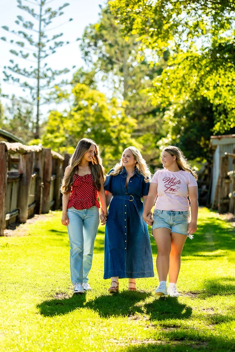 A mother with her two teenage daughters walking hand in hand a Fagan Park in Sydney's Hills District during an afternoon family outdoor photoshoot