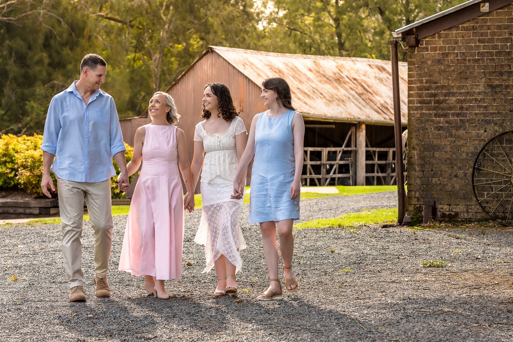 A woman celebrating her 50th birthday with a family photoshoot, while she and her family walk hand in hand at Fagan Park in the Hills District of Sydney