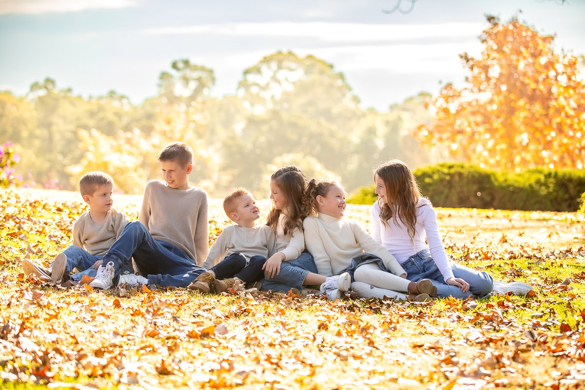 Young cousins sitting in autumn leaves looking at each other