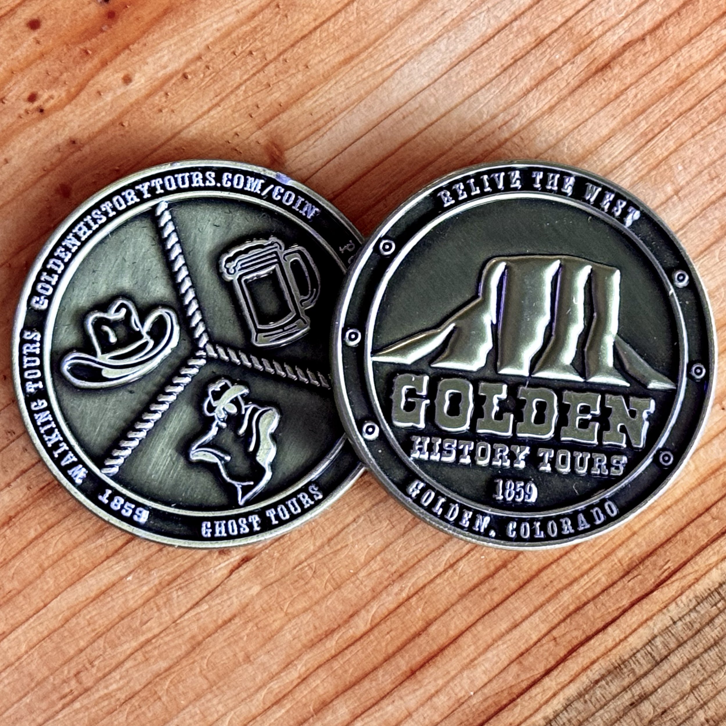 Front and back of a GHT coin on a wood background.