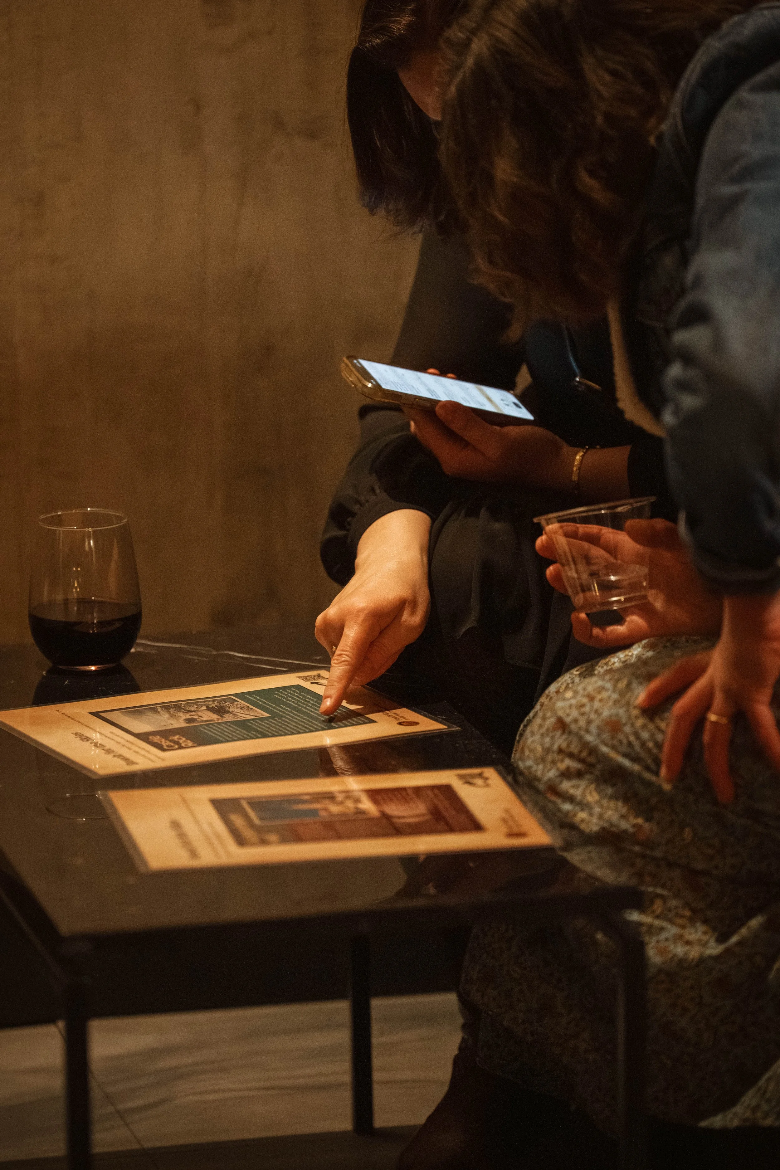 A person pointing to a scavenger hunt clue while holding a cell phone.