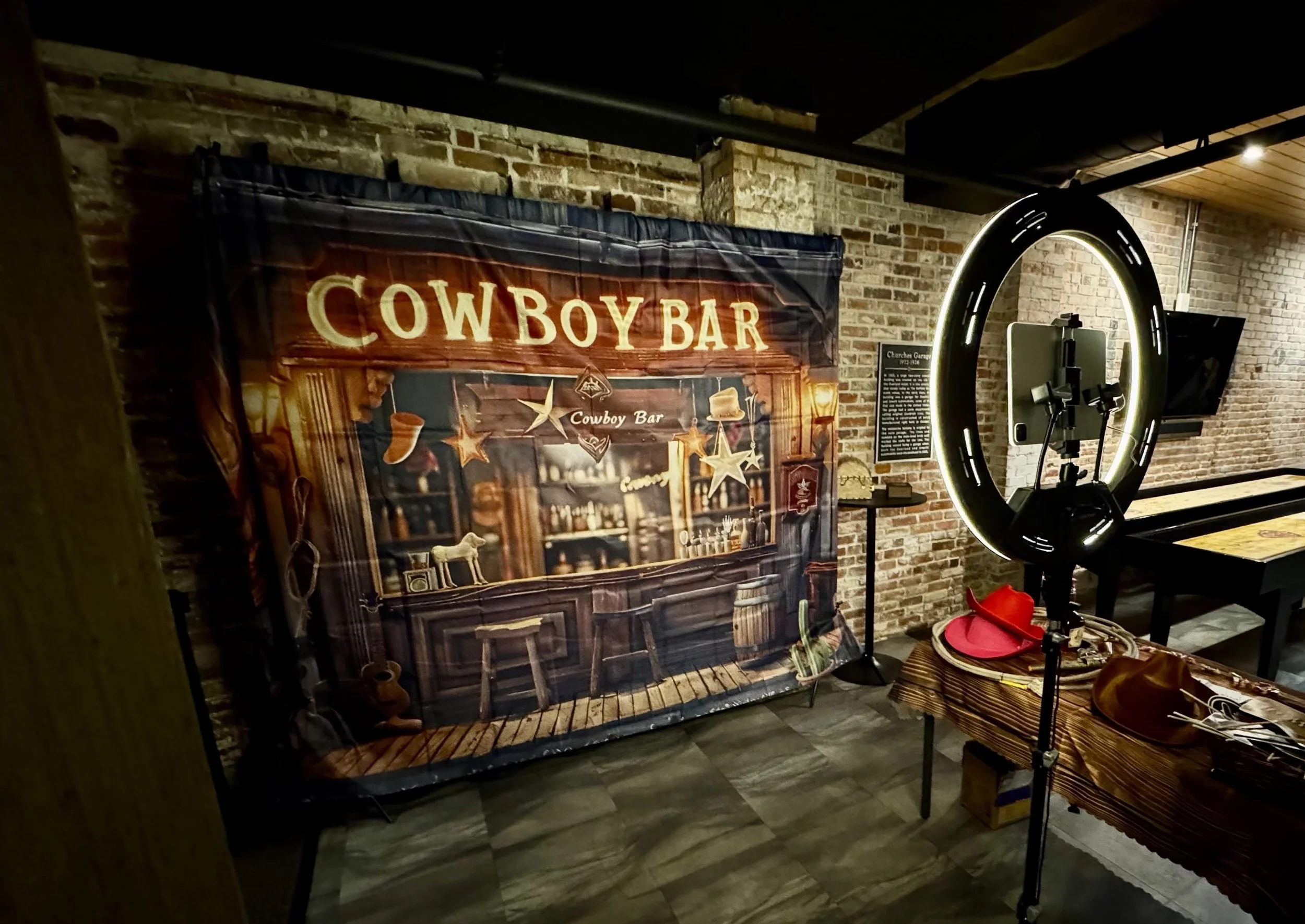 An iPad in a light ring facing a Cowboy Bar backdrop next to a table of props.