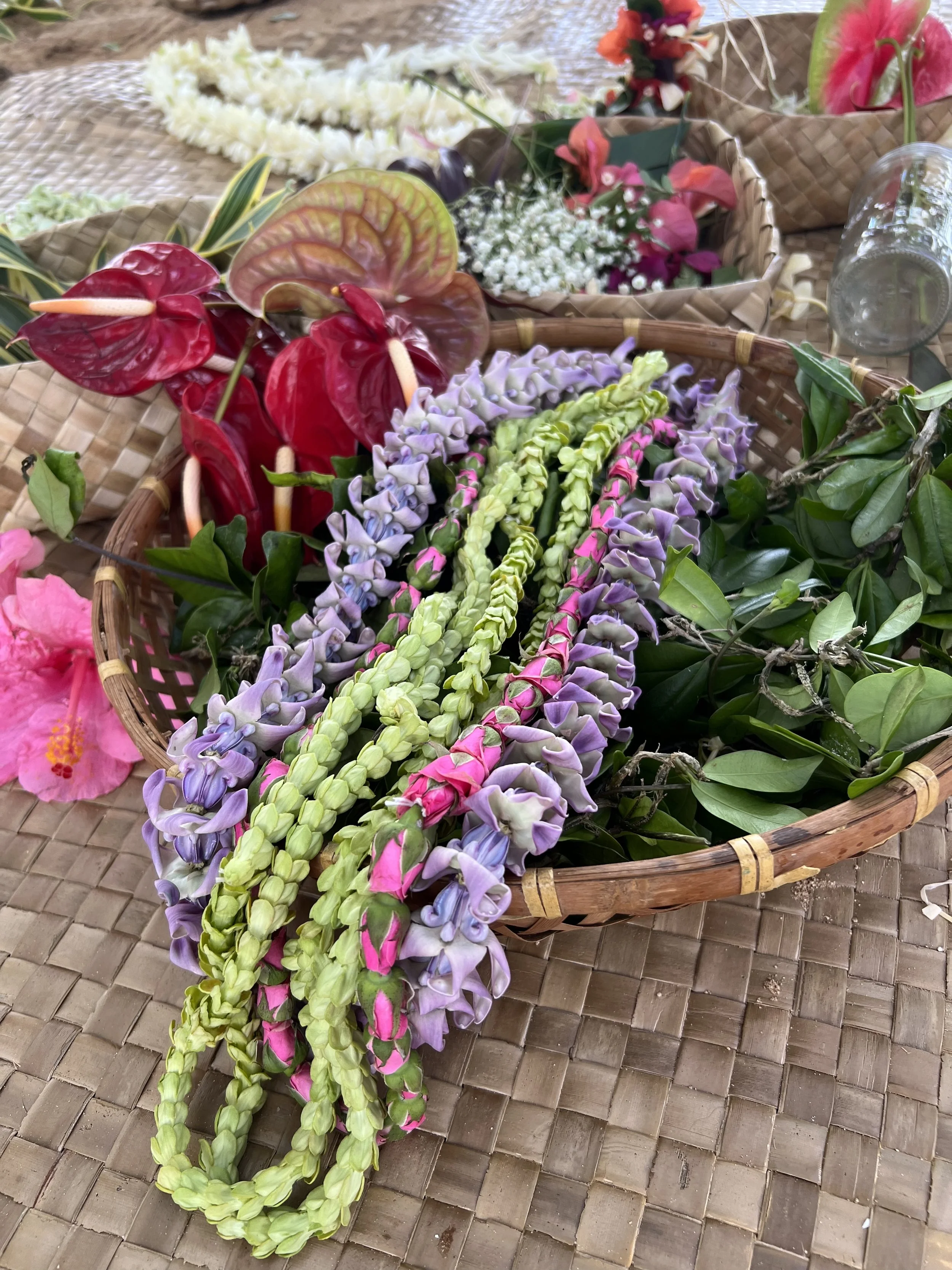 Colorful floral arrangement with purple, pink, green, and red flowers in woven baskets on a textured brown surface.