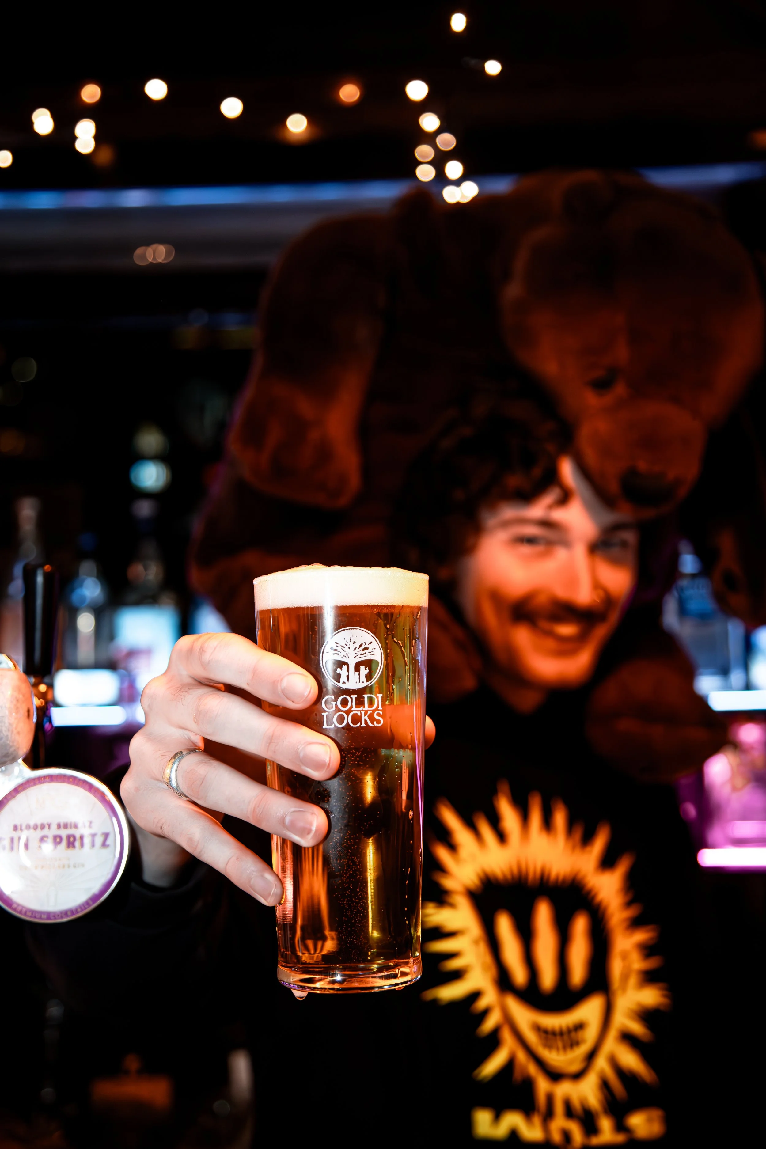 Goldilocks Rooftop Bar team member holding a beer at the bar, representing hospitality careers in Melbourne CBD.