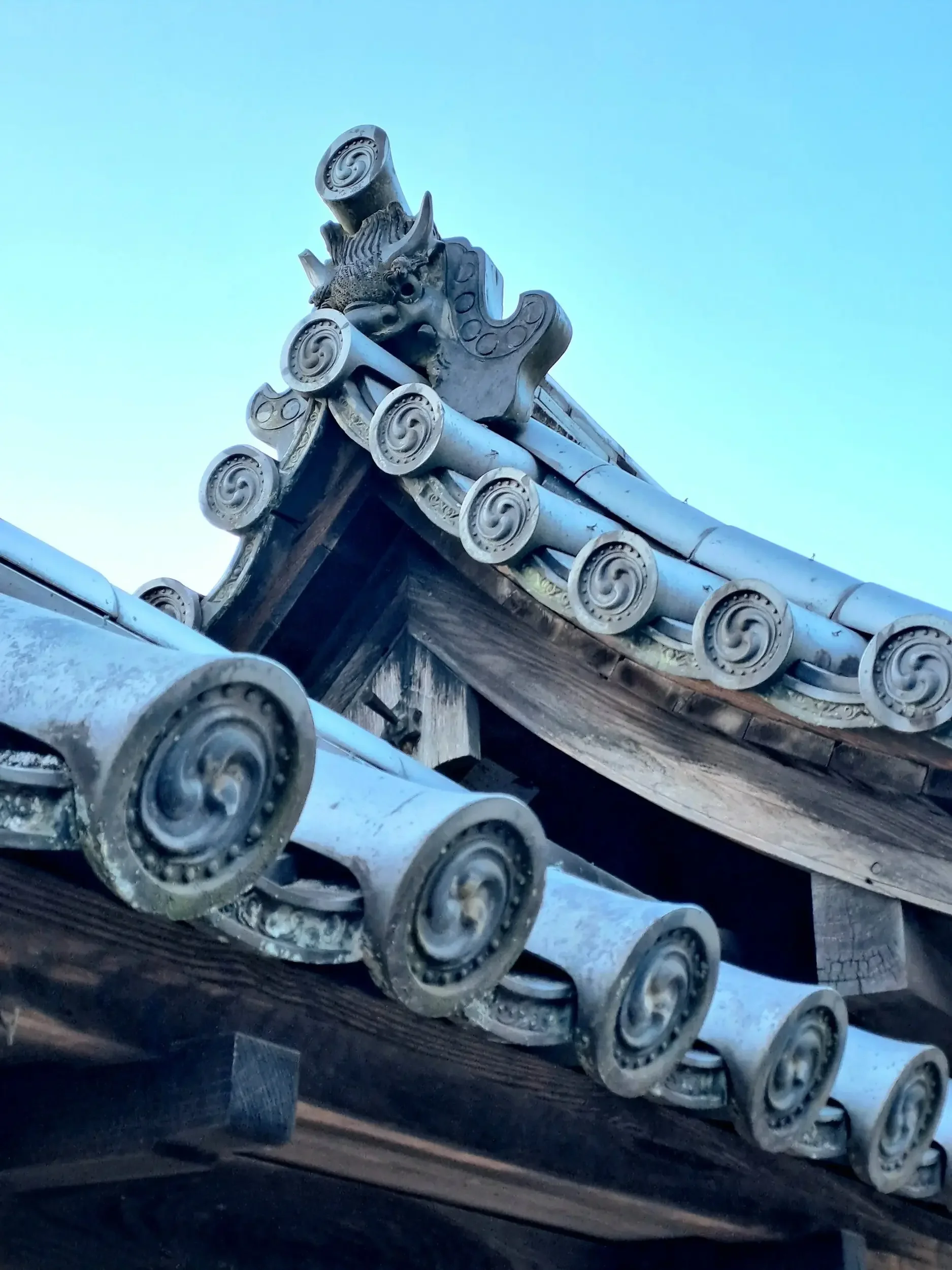 Traditional Japanese building made out of wood and stone. Hand-carved grey stone roof tiles and decorations.