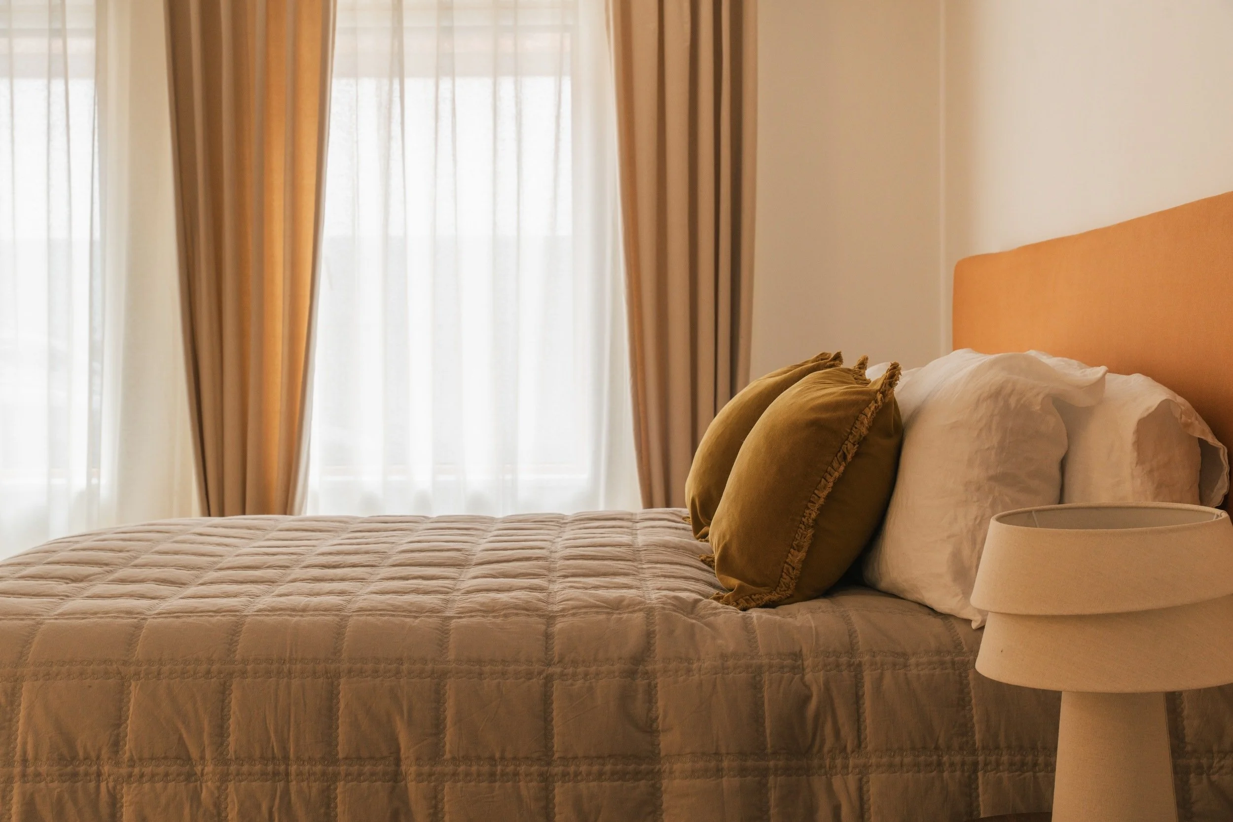 Image of the master bedroom. Ochre custom-made headboard. Ochre cushions on off-white bedsheets. Designed by San Stae Interior Design and Art Studio.