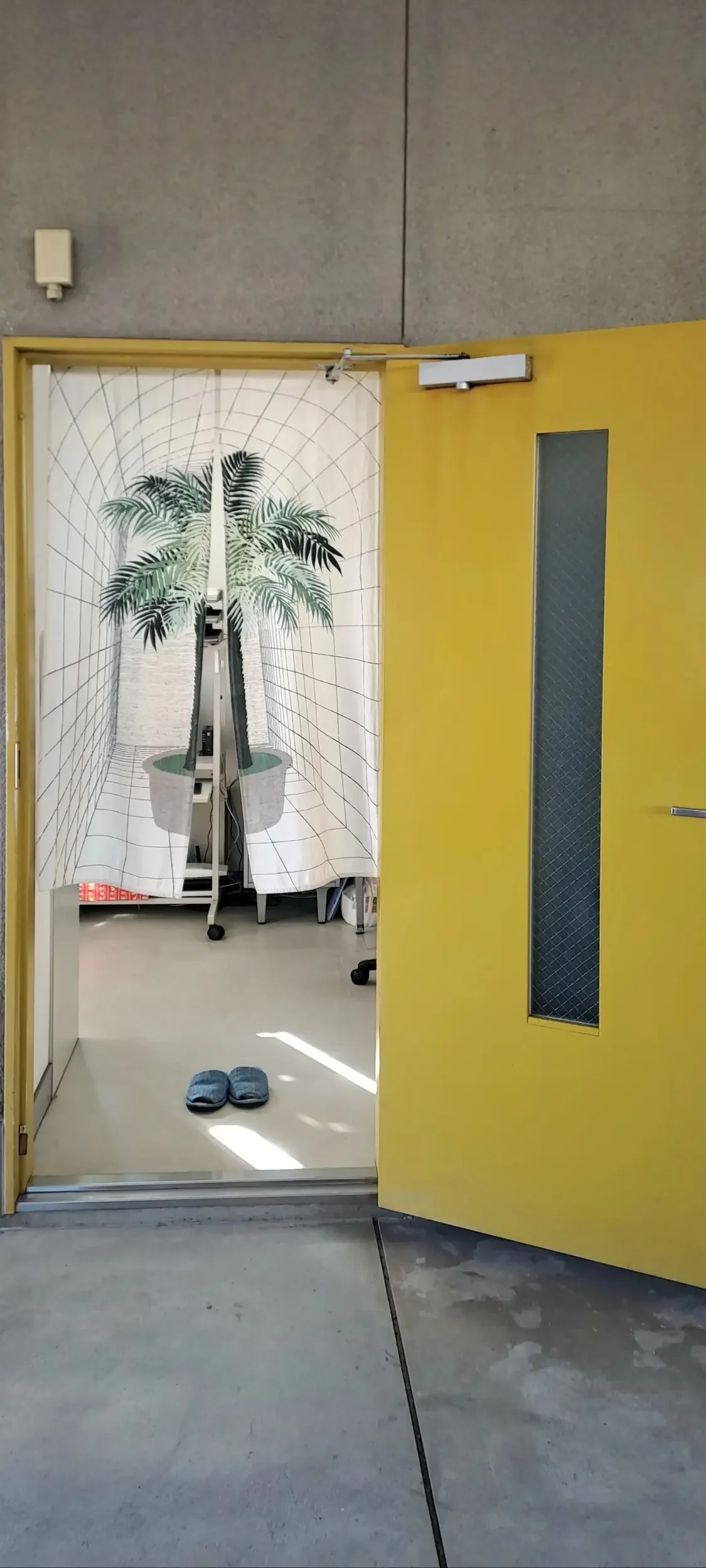 Room with a yellow fire door and slippers.
