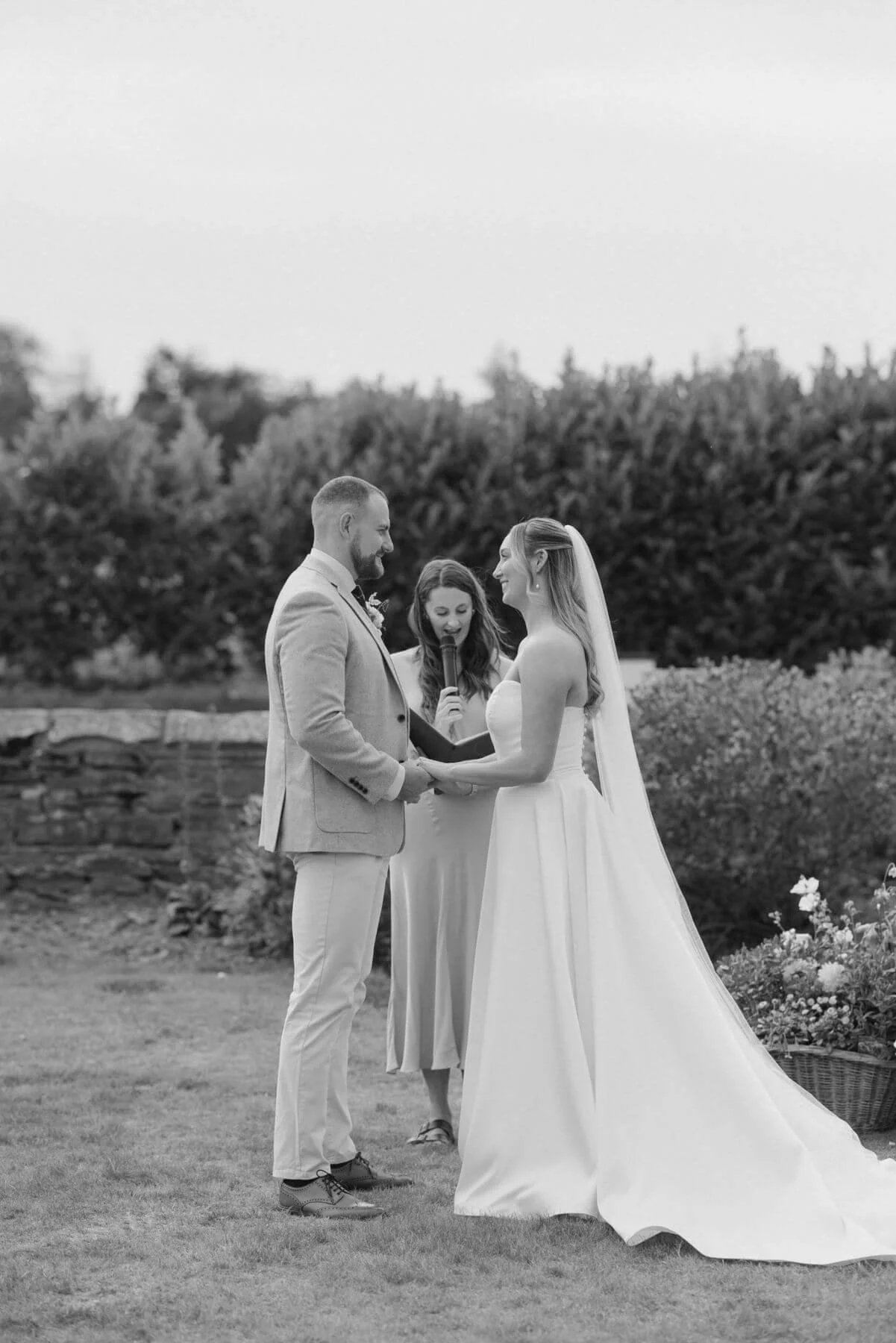 A summer wedding outside, Michelle Park Celebrant conducts a wedding in Richmond, North Yorkshire. The bride and groom are holding hands and looking at each other. 