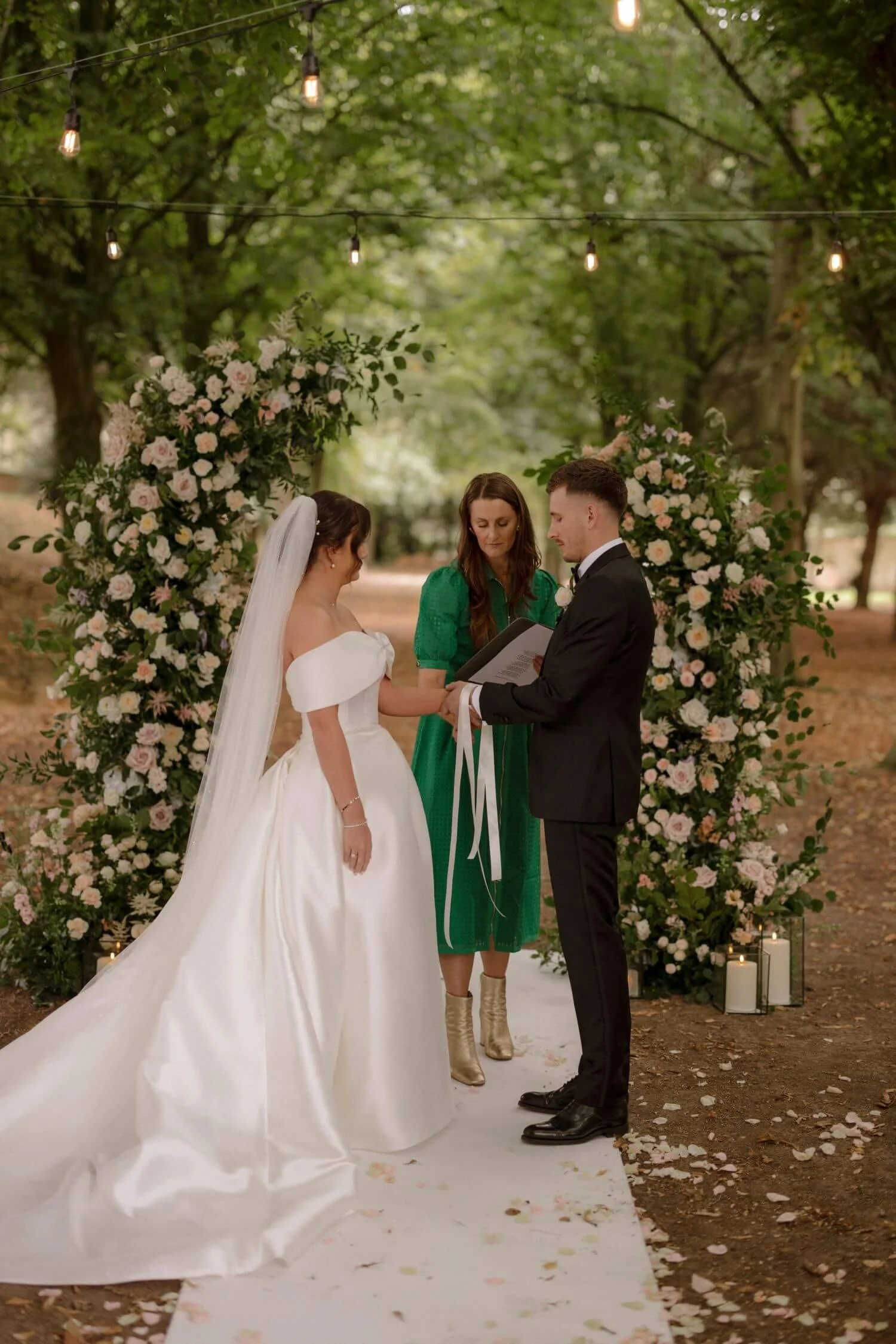 Michelle Park Celebrant drapes handtying cords over the wrists of a bride and groom at Saltmarshe Hall, East Yorkshire